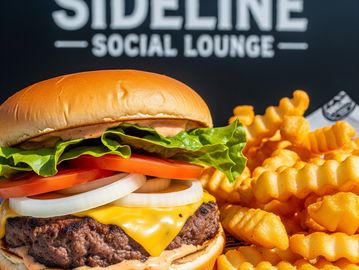 Juicy cheeseburger with lettuce, tomato, onion, and crinkle-cut fries on the side.