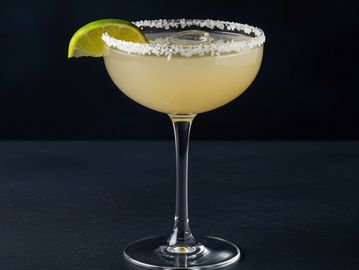 A margarita cocktail in a salt-rimmed glass with a lime wedge garnish.