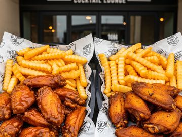 Two baskets of chicken wings and crinkle-cut fries at Sideline Social.