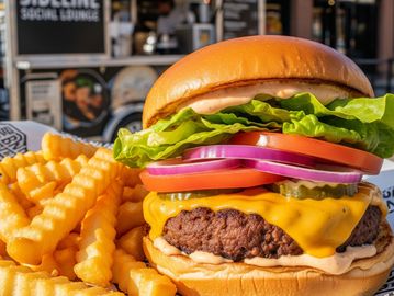 Cheeseburger with lettuce, tomato, onions, pickles, and crinkle-cut fries at Sideline Social Lounge.