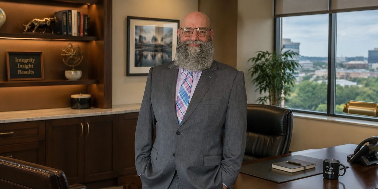 Smiling man with a beard in a suit standing in a professional office.