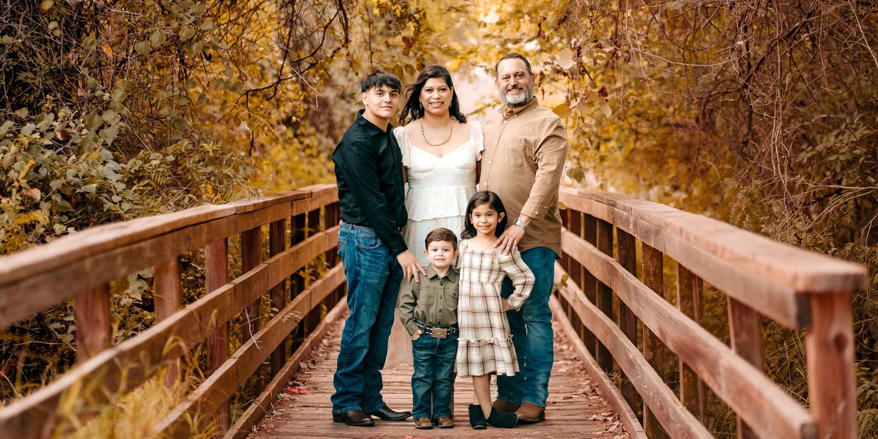 Family of five on a wooden bridge in autumn.