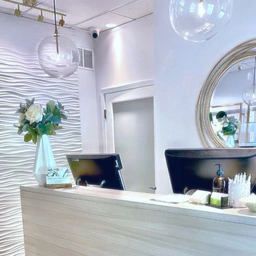 Modern reception desk with floral decor and round mirror in a bright, clean space.