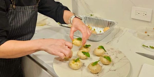 Hands assembling stuffed mushrooms with herbs.