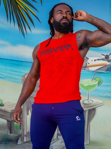 Man in a red sleeveless shirt posing by a tropical mural.