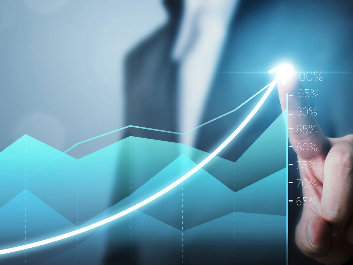 Businessman pointing at a glowing upward trend graph.