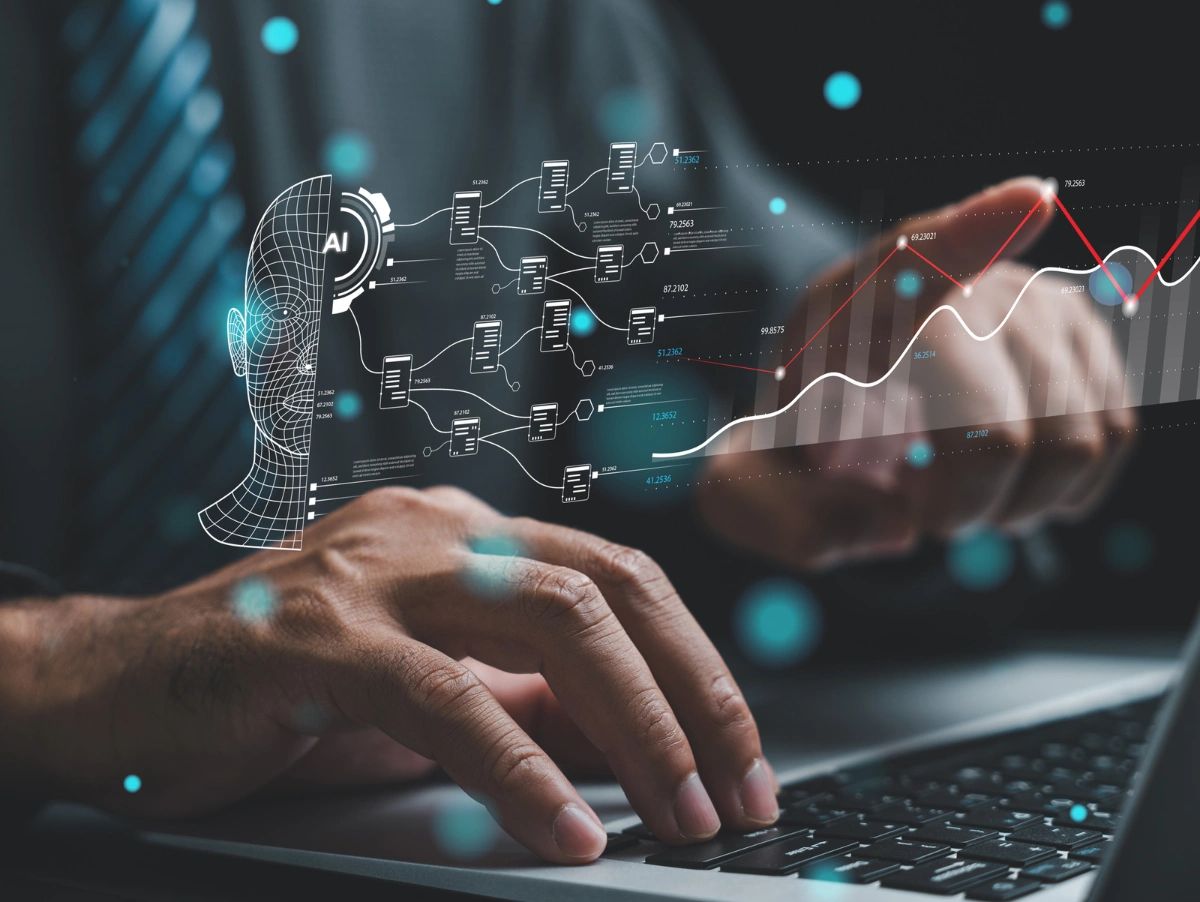 Hands working on a laptop with AI data visualization and graphs overlay.