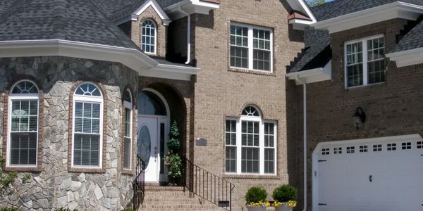 Elegant brick and stone house exterior with arched windows and a white garage door.