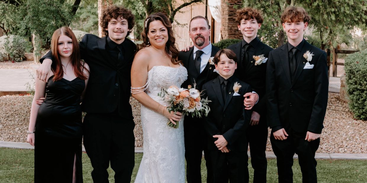 Wedding group photo with bride, groom, and family in formal attire.