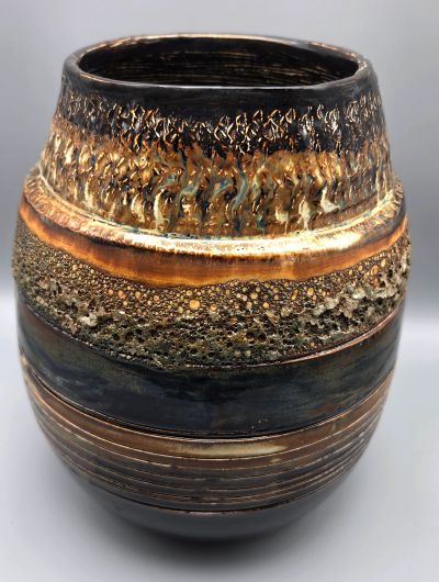 Decoratively textured ceramic vase with brown, gold, and black hues.