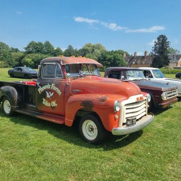Vintage GMC truck with Phoenix Farms Tulsa OK logo at a car show on a sunny day.