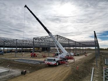 A crane lifting materials at a construction site with steel framework.