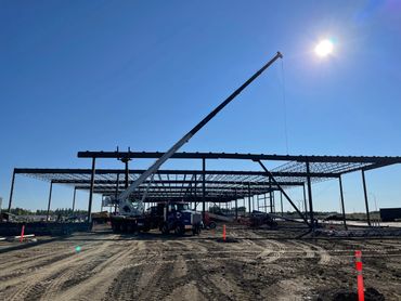 Construction site with crane lifting materials under clear blue sky.