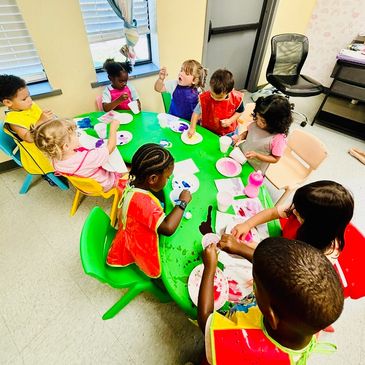Children gathered around a table doing arts and crafts.