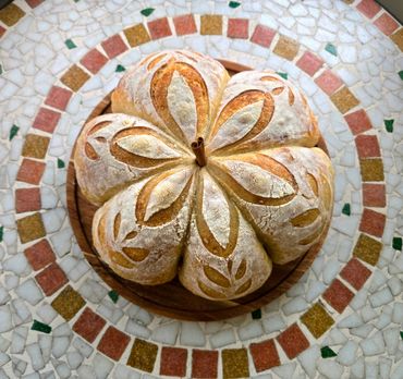 Artistic round bread with floral patterns on a mosaic tile surface.