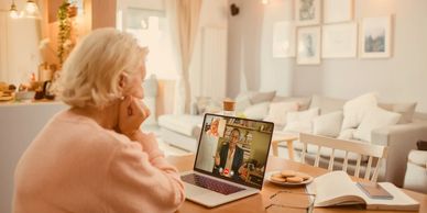 Elderly woman video chatting with a professional in a cozy home setting.