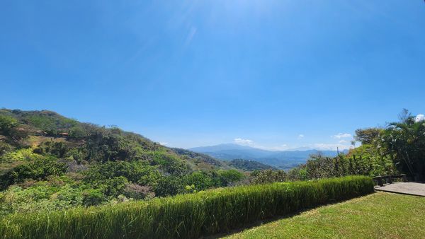Clear blue sky over lush green hills and mountains.