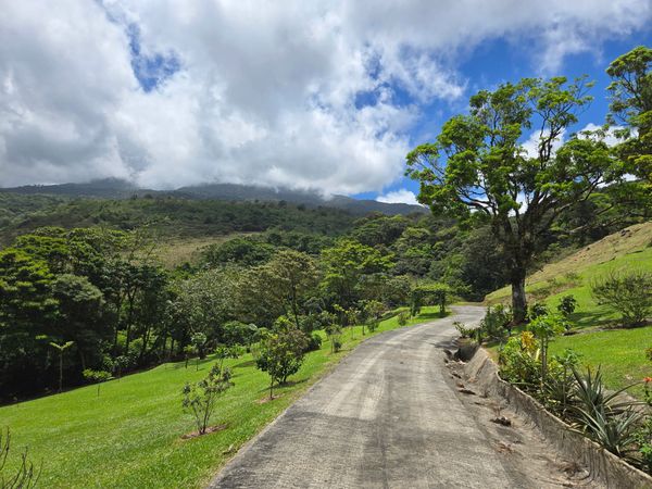 Winding road through lush green landscape under a partly cloudy sky.