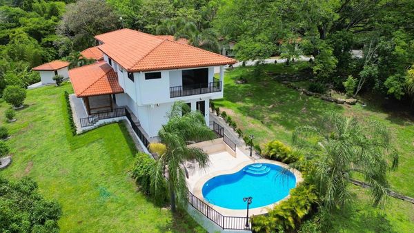 Modern two-story house with a red-tiled roof and a kidney-shaped pool.