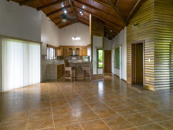 Spacious kitchen and living area with wood ceiling and tile flooring.