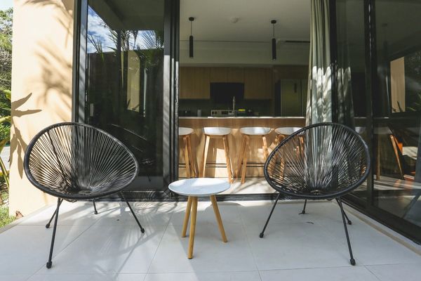 Modern outdoor seating with two black chairs and a small white table on a patio.