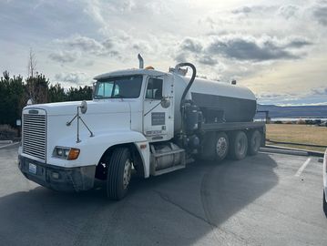 White tanker truck parked outdoors on a cloudy day.