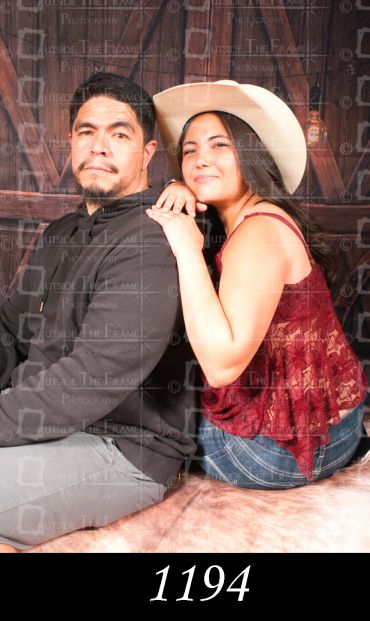 Couple posing back to back, woman wearing a cowboy hat.