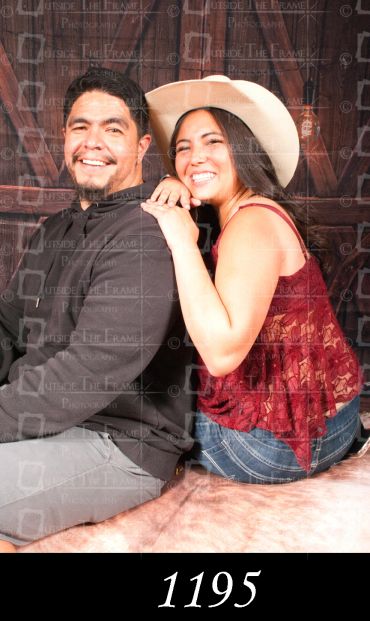 Smiling couple posing together, woman wearing a white hat.