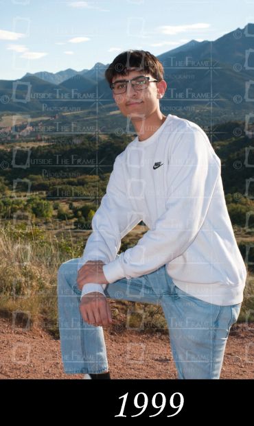 Young man posing outdoors with mountains in the background.