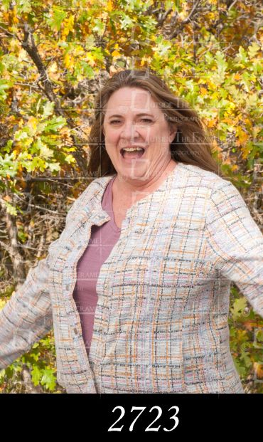 Smiling woman outdoors with autumn foliage background.