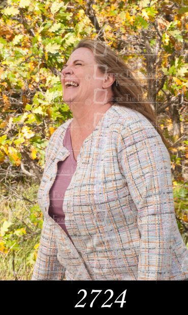 Woman laughing joyfully outdoors in autumn foliage.