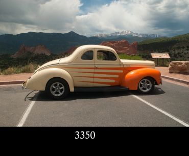 Classic vintage car parked with mountains in the background.
