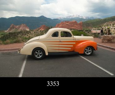 Classic car parked with scenic mountains in background.