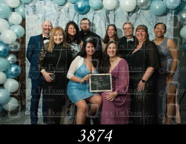 Group of ten people posing at an event with balloons in the background.