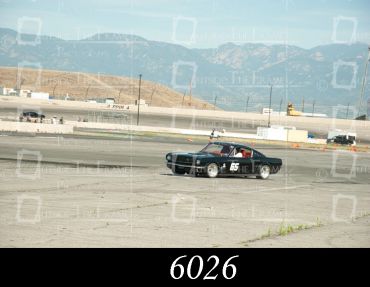 Black race car number 45 on a track with mountains in the background.