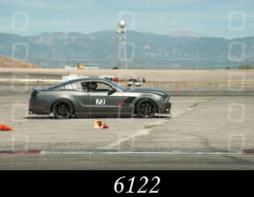 Gray sports car racing on a track during daytime.