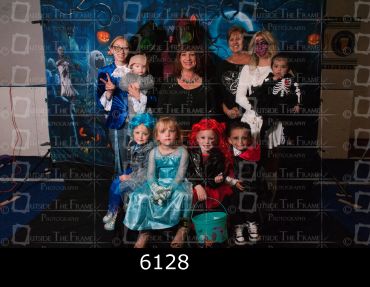 Group of children and adults in Halloween costumes posing for a photo.