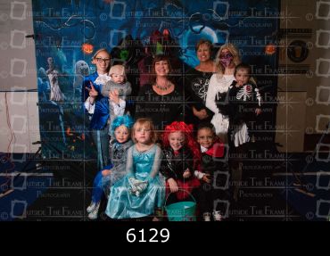 Group of children and adults in Halloween costumes posing for a photo.