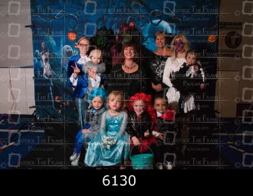 Group of children and adults in Halloween costumes posing for a photo.