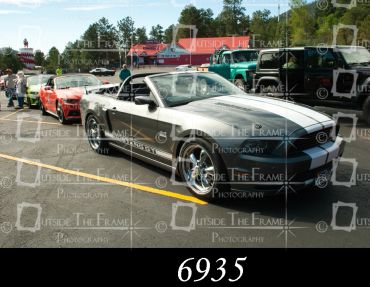Silver Ford Mustang convertible at a car show.