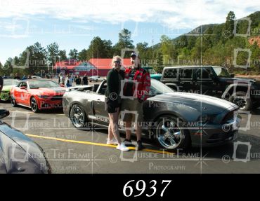 Couple posing near classic car at car meet.