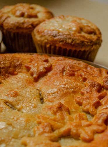 apple pie with fall leaves decoration with apple cup pies in the background