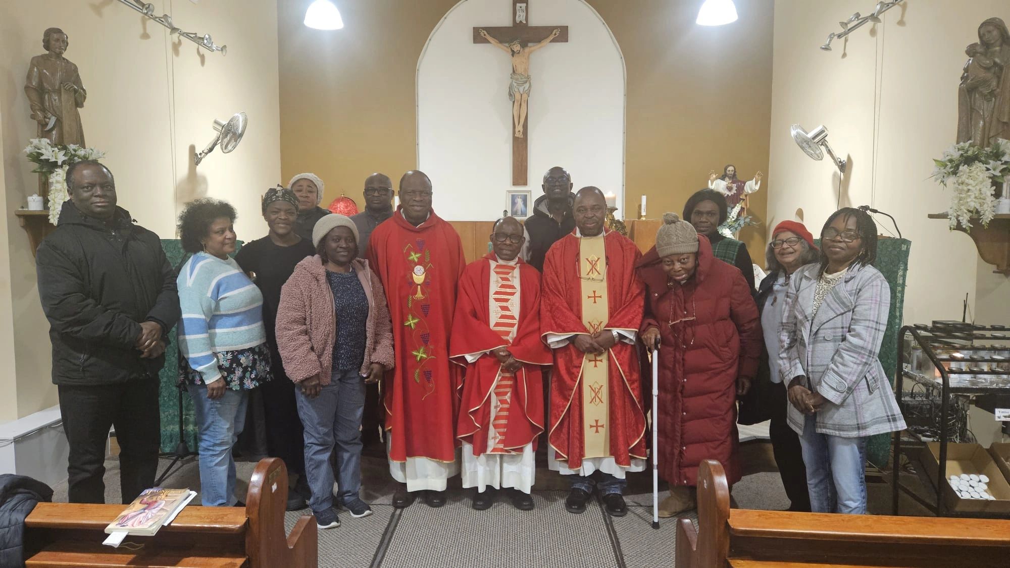 A group photo in a church with three priests and community members.