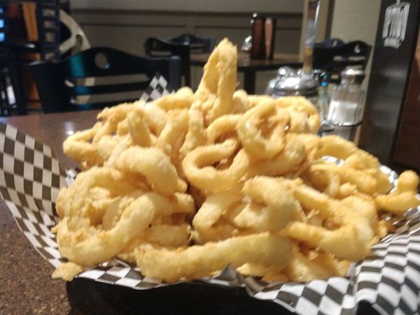A big basket of crispy, golden-brown onion rings.
