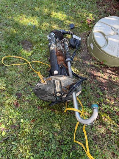 Old trolling motor lying on grass.