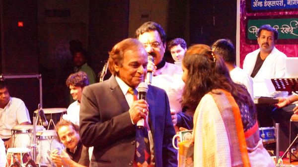 Kalyanji Anandji is talking to Yashashree Bhave during live music show on stage.