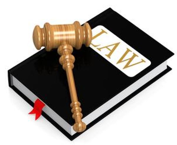 A wooden gavel rests on a black law book with a red bookmark.