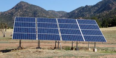 Solar panels installed in a rural area with mountains in the background.