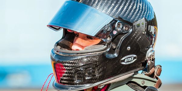 Close-up of a racer wearing a carbon fiber helmet with a blue visor.