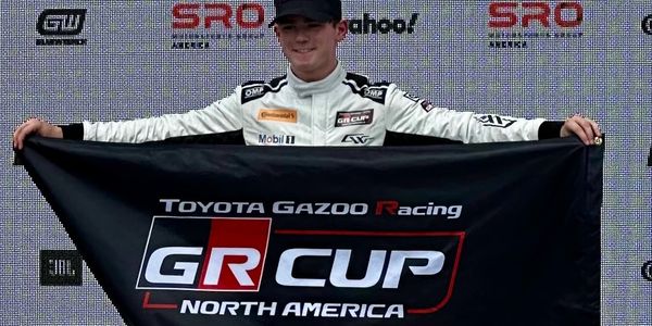 Young racer holding a Toyota Gazoo Racing GR Cup North America banner.